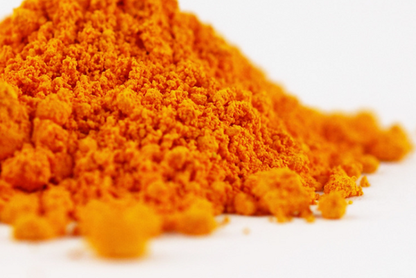 Loose mass of vibrant orange natural mineral pigment on a white surface.