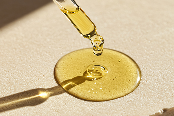 PROVISLIM® – innovative ingredient with lipolytic effect for body contouring. Drop of yellow serum with a pipette on a beige surface.